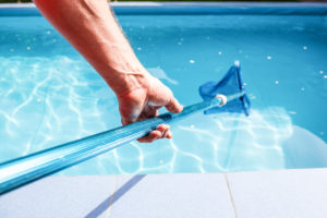 Pool pro skimming a swimming pool with a blue pool skimmer - leisure pool